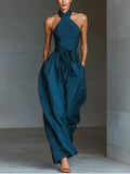 Mono azul marino con cuello halter cruzado, pierna ancha y bolsillos laterales