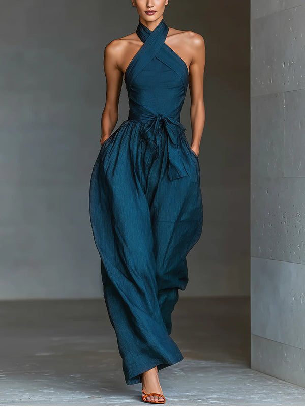 Mono azul marino con cuello halter cruzado, pierna ancha y bolsillos laterales
