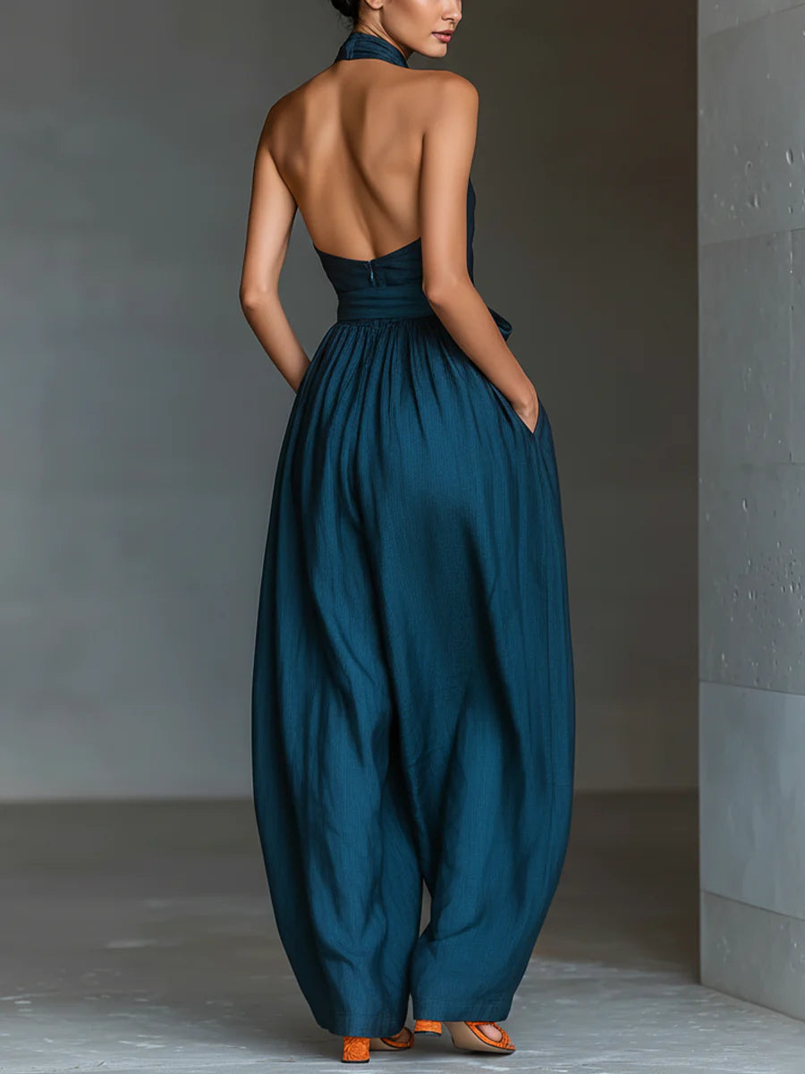 Mono azul marino con cuello halter cruzado, pierna ancha y bolsillos laterales